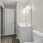 Modern bathroom in neutral tones featuring a sleek vanity with a large mirror and elegant lighting.