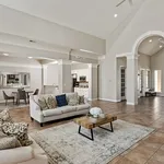 Spacious open-concept living room with elegant arches, cozy seating area, and inviting dining space.