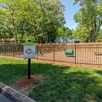 Charming fenced dog park with agility structures surrounded by lush greenery, perfect for pet-friendly apartments.
