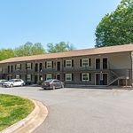 Charming two-story apartment building with a modern façade, surrounded by lush greenery and ample parking space.