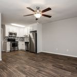 Modern open-concept kitchen with stainless steel appliances, elegant white cabinetry, and sleek hardwood flooring.