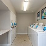 Bright and modern laundry room with multiple washing machines, dryers, and convenient folding counter.