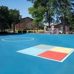 Vibrant outdoor recreational area with a bright blue sports court surrounded by lush greenery and modern apartment buildings, offering a perfect blend of active living and serene environment.