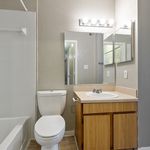 Modern bathroom with bright lighting, elegant vanity, and pristine bathtub, designed for comfort and style.