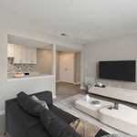 Modern living room with sleek furniture, open-concept layout, and adjacent kitchen featuring stylish backsplash.