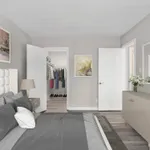 Chic bedroom with elegant gray bedding, spacious walk-in closet, and modern decor featuring stylish artwork and fresh flowers.