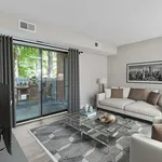 Bright and modern living room with plush sofa, glass coffee table, and sliding glass doors leading to a scenic balcony with outdoor seating.