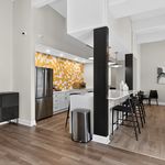 Modern and inviting kitchen area with a vibrant yellow mosaic backsplash, sleek stainless steel appliances, and a stylish breakfast bar with chic black seating.