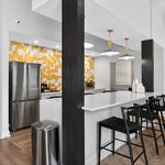 Modern kitchen with sleek bar seating, vibrant yellow geometric backsplash, and stainless steel appliances creating a stylish, inviting atmosphere.
