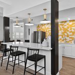 Contemporary kitchen featuring a sleek breakfast bar with chic black chairs, vibrant geometric backsplash, and elegant pendant lighting.