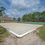 Inviting outdoor sand volleyball court surrounded by lush greenery and blue skies, perfect for recreation and relaxation.