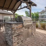Charming outdoor BBQ area with a sleek stone grill under a cozy covered patio, perfect for entertaining.