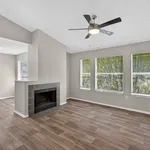 Charming living area with large windows, a modern ceiling fan, and a stylish fireplace, perfect for cozy relaxation.