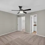 Inviting bedroom with plush carpet, modern ceiling fan, and walk-in closet, perfect for serene living.