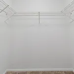 Spacious walk-in closet with clean white walls and ample shelf space, perfect for organizing your wardrobe.