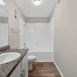 Bright and modern bathroom featuring sleek granite countertops, a spacious mirror, and elegant tile bathtub with soft lighting.