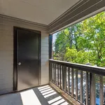 Charming apartment balcony with a wooden railing and lush green views, perfect for relaxation.