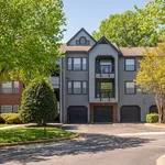 Charming multi-story apartment complex with modern design, surrounded by lush greenery and ample parking space.