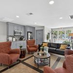 Inviting living space with plush orange chairs, a modern kitchen, and a cozy sofa, perfect for relaxation and entertaining.