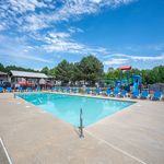 Inviting outdoor pool area with vibrant blue loungers and a charming playground, perfect for relaxation and family fun.
