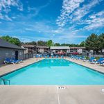 Inviting outdoor swimming pool with comfortable lounge chairs, surrounded by modern apartment buildings and lush greenery.
