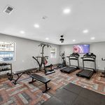 Bright and modern fitness room featuring state-of-the-art treadmills, weight benches, and a flat-screen TV for an energizing workout experience.
