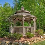 Charming wooden gazebo nestled in lush greenery, perfect for outdoor relaxation and gatherings.