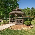 Charming wooden gazebo nestled in a lush, green park setting, perfect for relaxation and outdoor gatherings.
