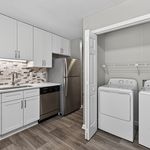 Modern kitchen with sleek stainless steel appliances, elegant white cabinetry, and adjacent laundry area for convenience.