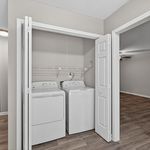 Charming in-unit laundry space with modern washer and dryer, adjacent to spacious room with sleek flooring.
