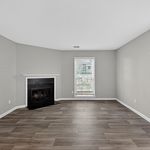 Bright, modern living room with elegant hardwood floors and a cozy fireplace, filled with natural light from a large window.