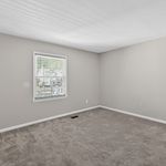 Bright and airy room with soft carpet and large window, perfect for a cozy retreat.