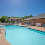 Inviting outdoor swimming pool with sun loungers and brick buildings in a serene residential setting.