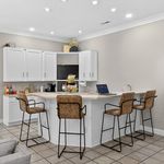 Modern kitchen with elegant bar seating, sleek white cabinets, and ambient lighting for a warm and inviting atmosphere.