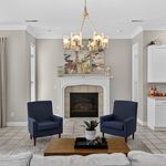 Elegant living room with cozy fireplace, modern chandelier, and stylish navy armchairs, creating a warm and inviting atmosphere.