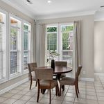 Bright dining area with natural light streaming through large windows onto a cozy table for four, perfect for intimate gatherings.