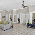 Bright and airy living space with modern ceiling fans, neutral tones, and elegant tile flooring, perfect for comfortable living.