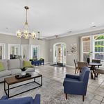 Elegant open-concept living area featuring modern furnishings, stylish chandelier, and large windows offering abundant natural light.