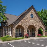 Charming stone-clad building with archways, set in a lush green environment, perfect for serene living.