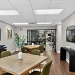 Elegant common area with stylish tables, inviting seating, and modern decor, adjacent to a state-of-the-art fitness center.