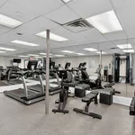 Modern fitness center with state-of-the-art treadmills, exercise bikes, and strength training equipment in a mirrored room.