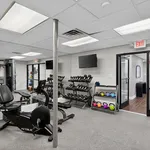 Modern fitness center with a range of equipment including cardio machines, dumbbells, and colorful kettlebells under bright lighting.