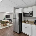 Modern kitchen with granite countertops, stainless steel appliances, and adjacent dining area featuring stylish table and chairs.