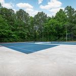 Inviting outdoor tennis court surrounded by lush greenery and serene trees, offering a perfect retreat for sports enthusiasts.