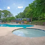 Inviting community swimming pool with a relaxing ambiance, surrounded by lush greenery and stylish residential buildings.