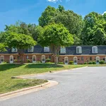 Charming row of brick townhouses with lush greenery, offering serene living amid nature's beauty.