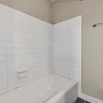Elegant bathroom with pristine white tiles and inviting bathtub, perfect for a relaxing retreat.