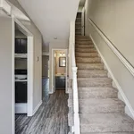 Inviting hallway with elegant staircase, leading to a cozy bathroom and modern kitchen.
