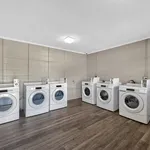 Modern communal laundry room equipped with multiple washers and dryers, featuring sleek machines and a clean, spacious design.