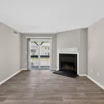 Bright living room with elegant fireplace, sleek wood flooring, and sliding glass doors opening to a scenic balcony view.